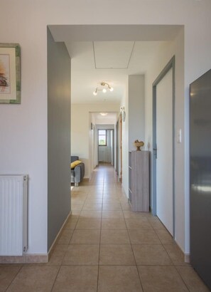A hallway with a radiator, a framed picture on the wall, and a grey sofa in the distance. - LA Prairie - Drumettaz Clarafond (DRUMETTAZ CLARAFOND)