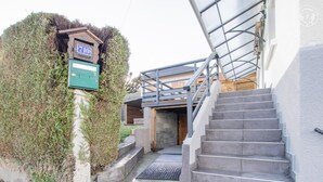 Een trap die leidt naar een houten terras met een brievenbus en een groen bord.
