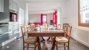 Een moderne keuken met een inbouwoven en een eethoek met een houten tafel en stoelen.