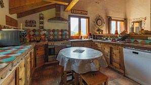 A rustic kitchen with wooden beams, a stove, a sink, and a dining table.