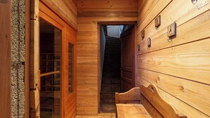 A wooden interior with a bench and a door leading to a dark room.