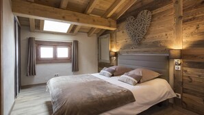 Un dormitorio con techo de madera, una cama con cabecera gris y una decoración en forma de corazón en la pared.