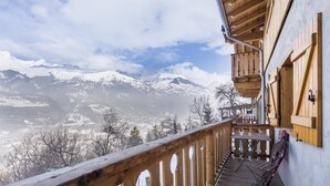 Un balcón de madera con vistas a montañas nevadas.