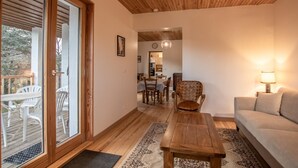A cozy living room with a wooden ceiling, a sofa, a coffee table, and a dining area with chairs and a table. - Chalet Belledonne - LA Thuile (LA THUILE)