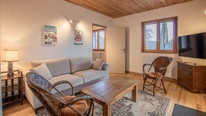 A cozy living room with a wooden ceiling, a sofa, a coffee table, a TV, and a chair. - Chalet Belledonne - LA Thuile (LA THUILE)