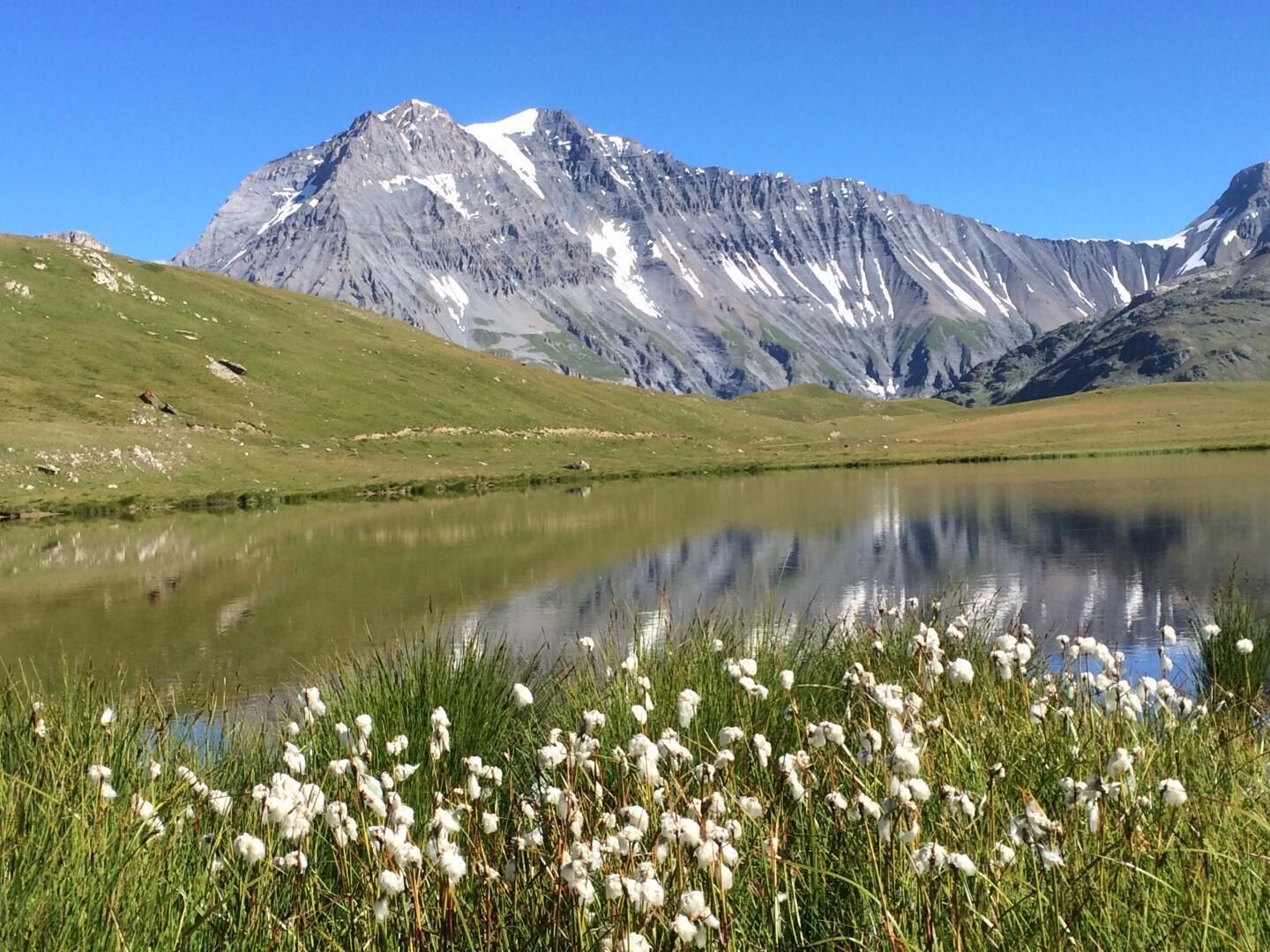 A mountain landscape with a lake and grassy foreground.
