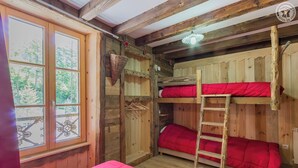 Una habitación rústica de madera con literas, una escalera y una ventana con vistas a árboles.