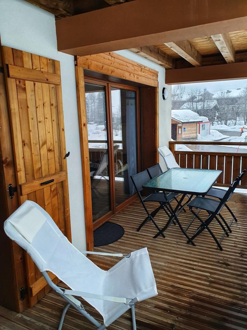 Un espacio al aire libre techado con mesa y sillas, una puerta de madera y vistas a un paisaje nevado.