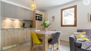Una cocina moderna con armarios de madera, una mesa de comedor con sillas y un sofá con una manta.