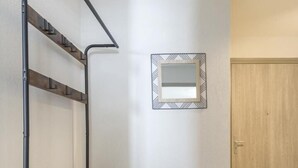 Una habitación pequeña con una cama nido, una silla, un espejo y una puerta.
