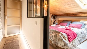 Una camera da letto con un letto, un soffitto in legno e un lucernario.