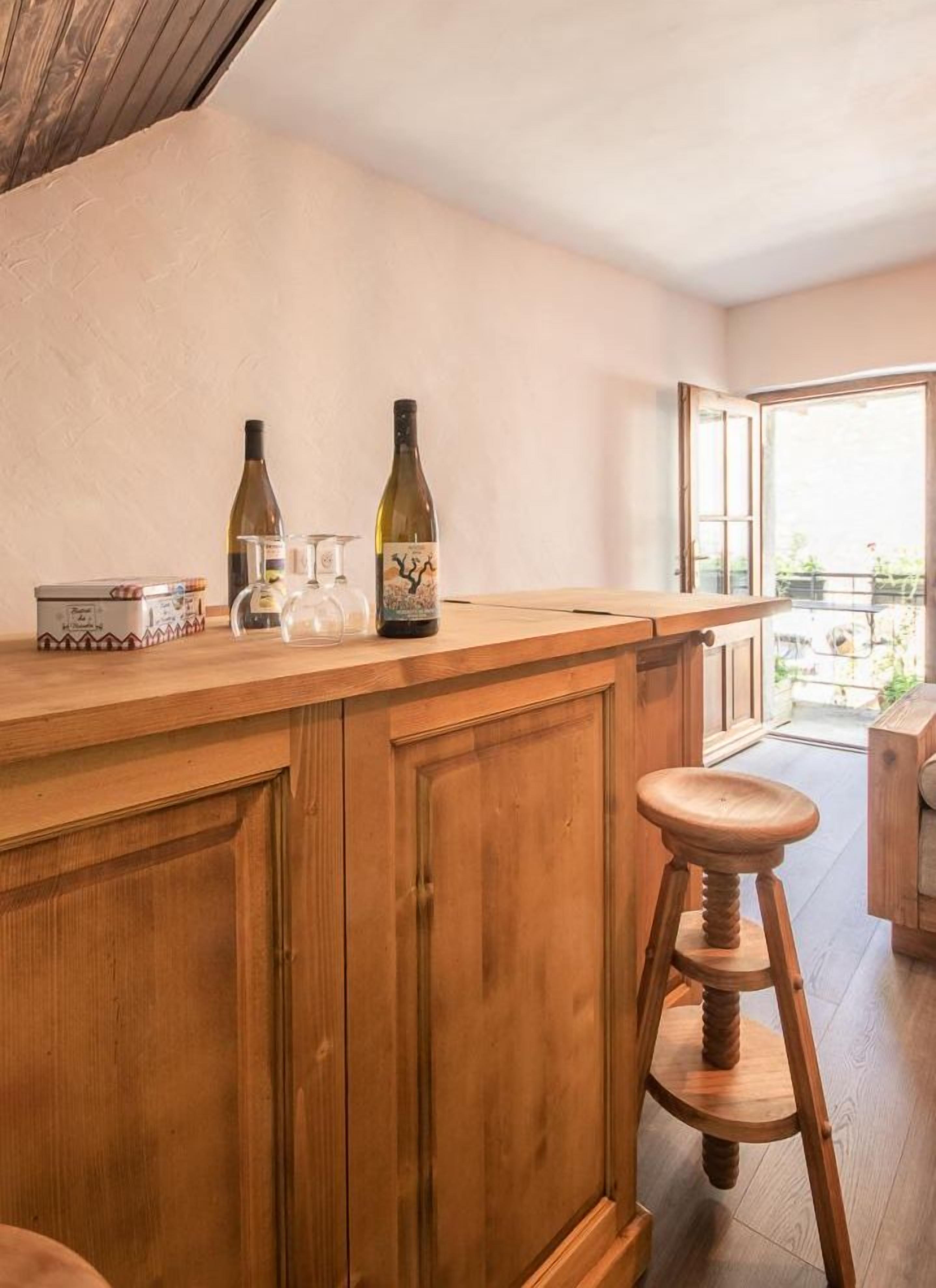 Eine Bar aus Holz mit zwei Weinflaschen, Gläsern und einer kleinen Box, vermutlich für Snacks.