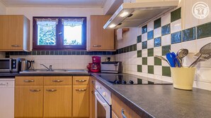 A kitchen with wooden cabinets, a microwave, a coffee maker, and a tiled backsplash.