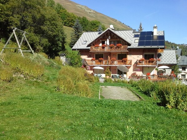 Un bâtiment de style chalet, doté d’un toit en pente, de balcons en bois et de panneaux solaires.