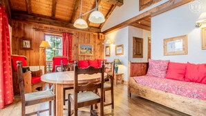 A cozy wooden interior with a dining table, chairs, and a sofa.