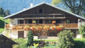 A wooden chalet with a balcony, surrounded by lush greenery and mountains. - LE Glopet - Hauteluce-les-saisies (HAUTELUCE-LES-SAISIES)