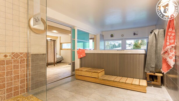 A bathroom with a shower, a wooden bench, a towel rack, and a view of the outside. - LE Glopet - Hauteluce-les-saisies (HAUTELUCE-LES-SAISIES)