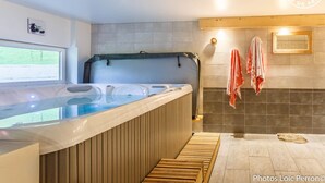 A modern bathroom with a large bathtub, wooden benches, a window, and a towel rack. - LE Glopet - Hauteluce-les-saisies (HAUTELUCE-LES-SAISIES)