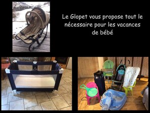 Een kinderwagen, babybedje en babyartikelen op een houten vloer.