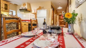 A dining area with a table set for two, a bottle of wine, and a vase with flowers. - LE Glopet - Hauteluce-les-saisies (HAUTELUCE-LES-SAISIES)