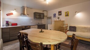 Une cuisine moderne avec des meubles de couleur sombre, une table à manger en bois et un grille-pain rouge.