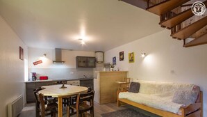 Un espace de vie compact comprenant un coin repas, une kitchenette et un canapé.