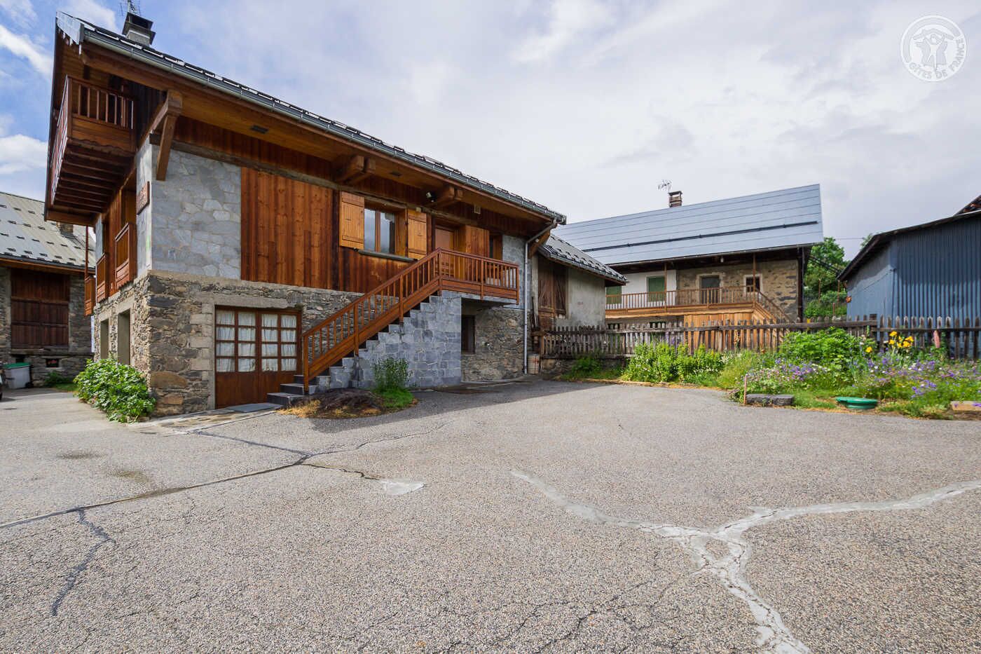 A rustic stone building with wooden balconies and a staircase leading to the entrance.