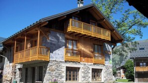 Ein traditionelles Chalet mit Steinaußenwand, Holzbalkonen und blauem Himmel.