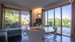 A modern living room with a dining area, large windows, and a view of the outdoors. - L'aromatique - Chignin (CHIGNIN)