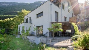 A modern two-story house with a flat roof, large windows, and a wooden deck. - L'aromatique - Chignin (CHIGNIN)