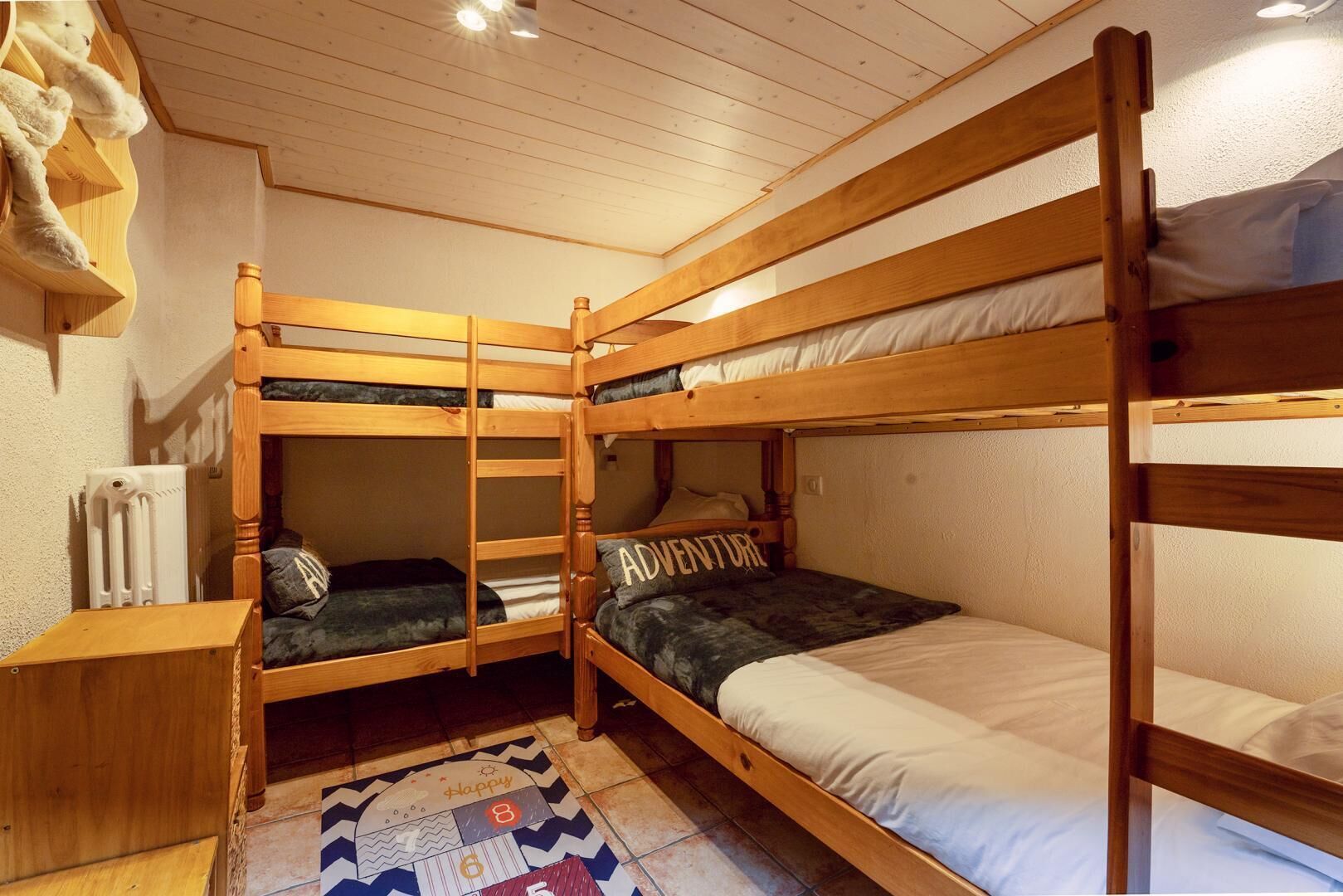 A bunk bed room with a radiator, a wooden shelf, and a patterned rug.