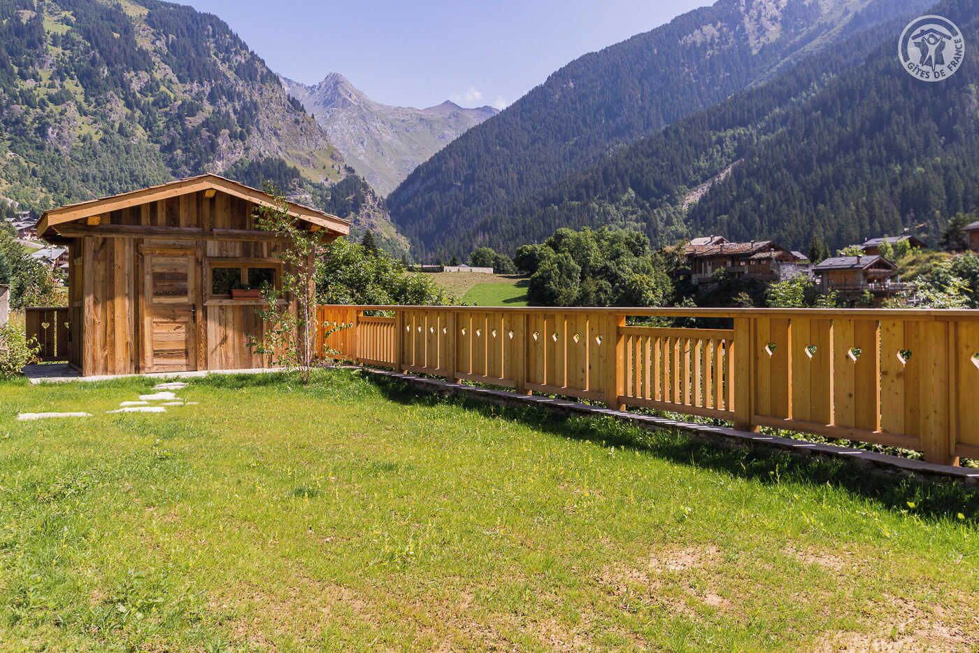 Un chalet en bois, entouré d’une clôture en bois, situé dans une région montagneuse.