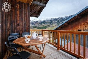 A wooden deck with a table and chairs, overlooking a mountainous landscape. - LE Rebellin - LA Lechere (LA LECHERE)