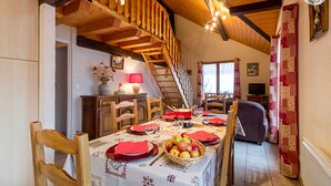 A dining area with a wooden staircase, a table set for four with red napkins and a fruit basket. - LES Diablotins - St-francois-longchamp (SAINT FRANCOIS LONGCHAMP)