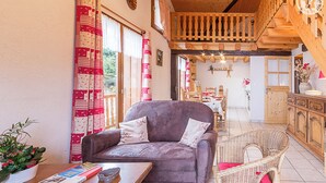 A cozy living room with a sofa, wicker chairs, a dining area, and a wooden staircase. - LES Diablotins - St-francois-longchamp (SAINT FRANCOIS LONGCHAMP)