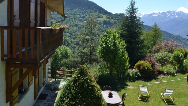 A balcony with wooden railings overlooking a garden with a table and chairs, and a mountainous landscape in the background. - LES Diablotins - St-francois-longchamp (SAINT FRANCOIS LONGCHAMP)