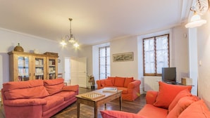 A living room with two orange sofas, a wooden coffee table, and a bookshelf.