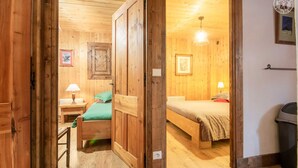 Ein Zimmer aus Holz mit zwei Betten, einem Tisch und einem Stuhl.