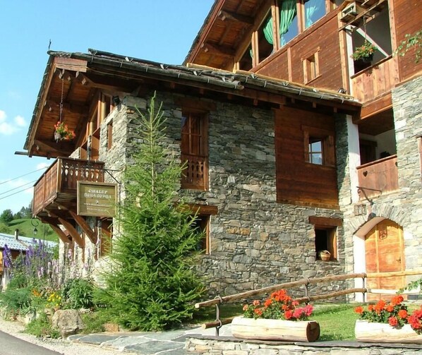 A traditional chalet with stone walls, wooden balconies, and a sign indicating it is a chalet.