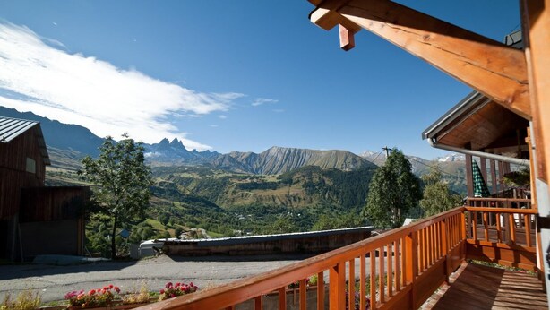 A wooden balcony with a view of a mountainous landscape.