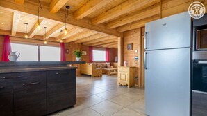 Una cocina moderna con una isla grande, un refrigerador empotrado y un comedor con mesa y sillas de madera.