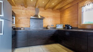 Una cocina moderna con armarios oscuros, una campana extractora de acero inoxidable y una ventana con vistas al campo.