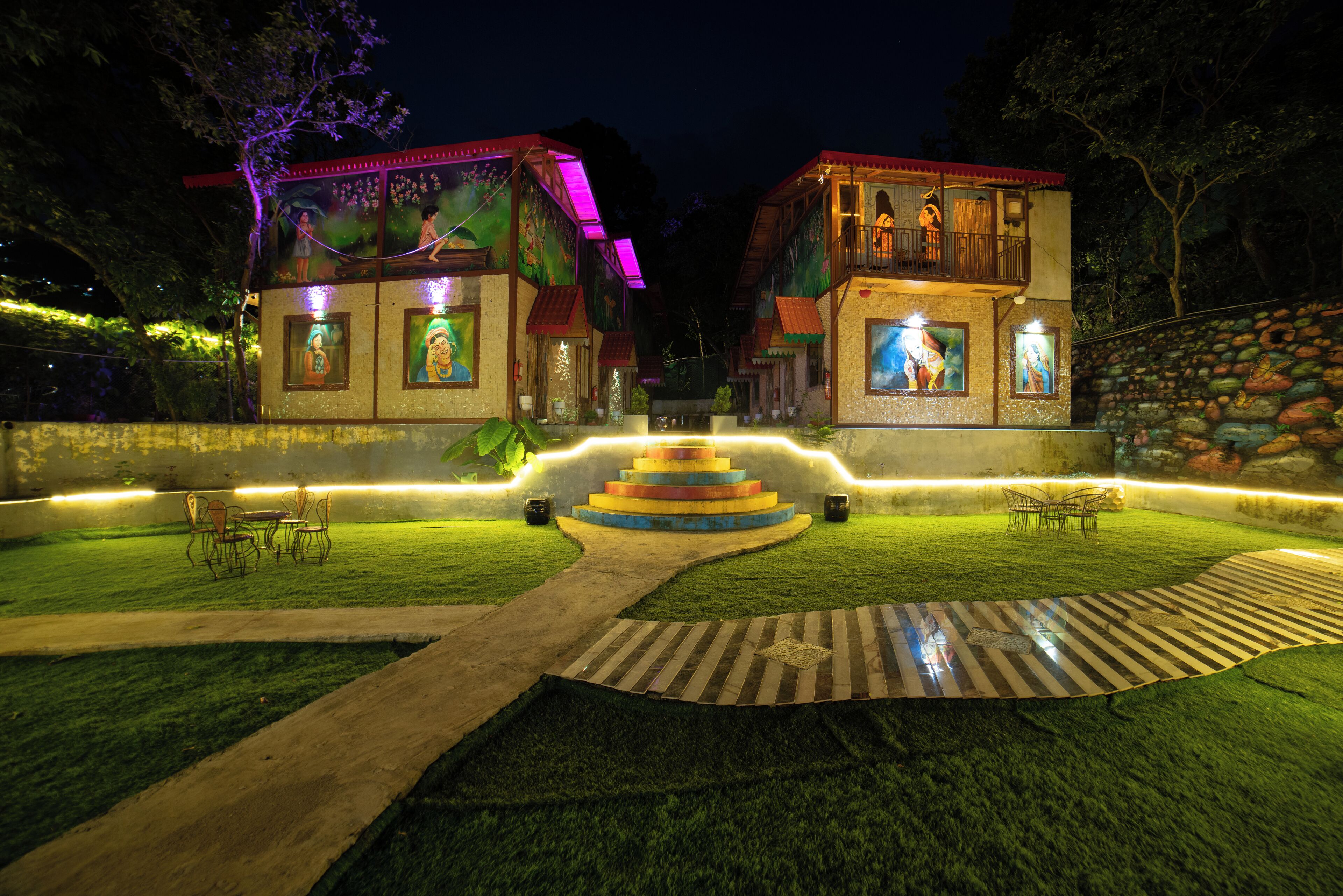 A hotel with a central staircase, outdoor seating, and a well-lit garden area.