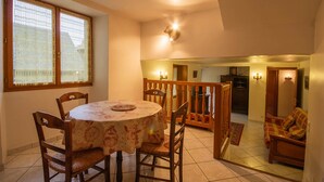 A dining area with a round table, four chairs, and a window with patterned curtains. - LES Mentens - Mouxy - Gîte (MOUXY)