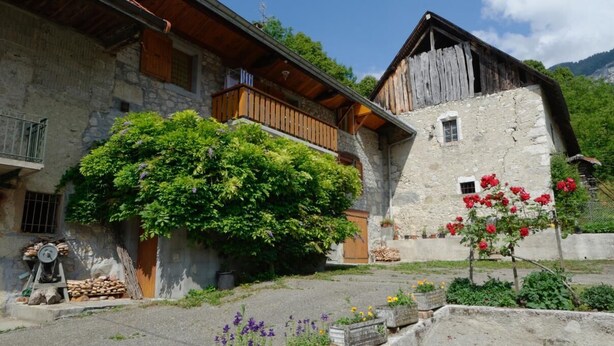A rustic stone building with a wooden balcony and a small window. - LES Mentens - Mouxy - Gîte (MOUXY)