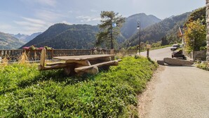 Un camino montañoso pintoresco con bancos de madera y un sendero de piedra.
