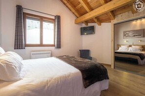 Een slaapkamer met een bed, een stoel, een televisie en een spiegel die een ander bed weerspiegelt.