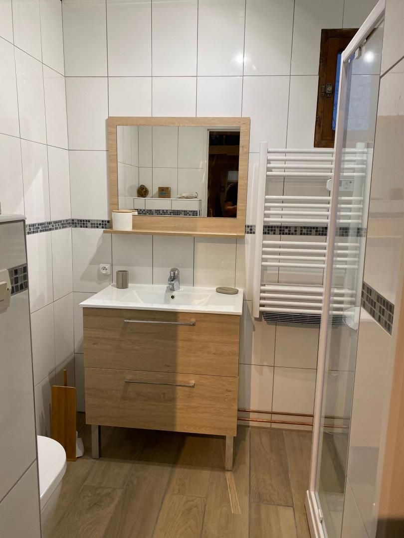 A bathroom with a white sink, wooden vanity, and a mirror.