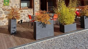 Una cabaña de madera con paredes de piedra, mobiliario exterior y cielo despejado.