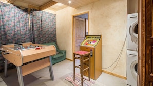 Een kamer met een tafelvoetbaltafel, een speelautomaat voor een kansspel en een wasmachine.